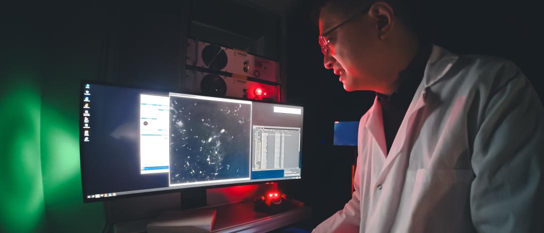 Ju Lu looks at a computer in the lab